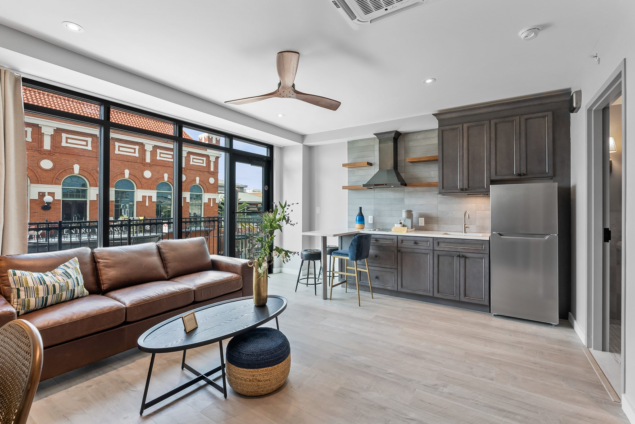 Suite Living & Gourmet Kitchen - Spacious boutique suite layout with exposed brick, quartz counters, and hardwood floors. | Sterling Suites Ybor City Tampa
